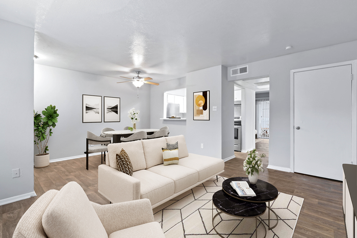 living room, hardwood style flors with rug, round black coffee table, ceiling fan, beige couch and cushioned chair, wall art