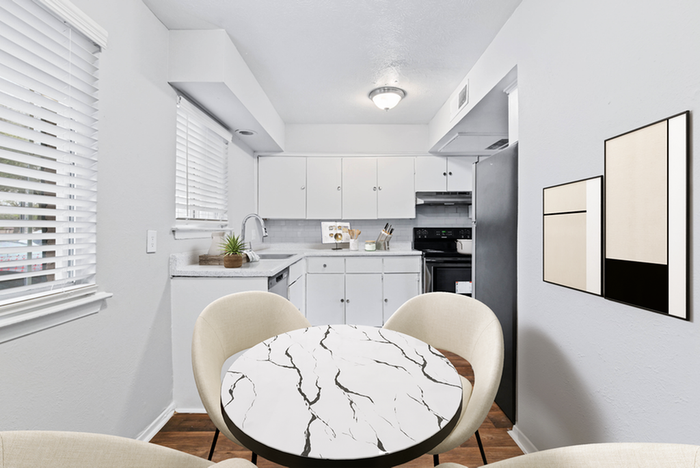 Dining area with round table, beige chairs, mirror wall art