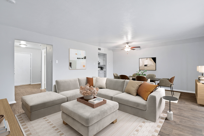 Living room, large beige sectional couch and center ottoman, hard wood style flooring, ceiling fan light fixture