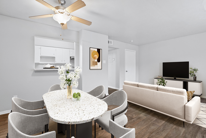 Round table, ceiling fan, cray chairs, beige couch, flat screen TV, hard wood style flooring