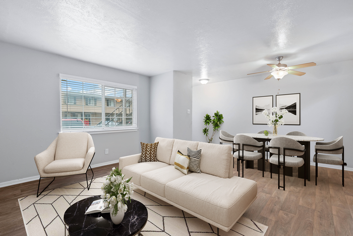 Living room, hard wood style flooring, rug, beige couch and beige chair, ceiling fan, black round coffee table,