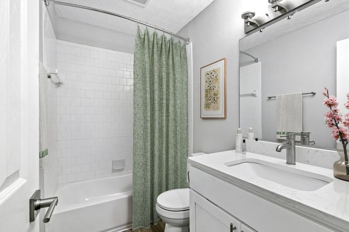 Bathroom with quartz counters, large mirror, Bathroom with quartz counters, large mirror, vanity lighting, and white cabinetry