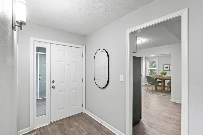 Virtual staging of entryway and dining room with hardwood floors