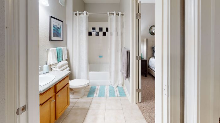 staged model of bathroom with granite style countertops and wood cabinets