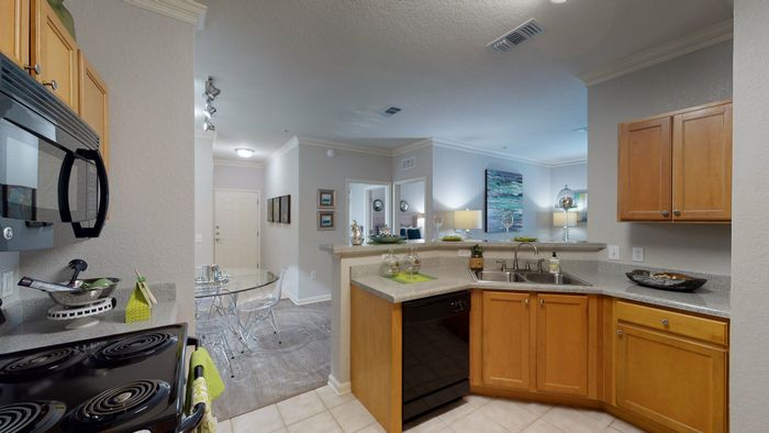 staged model of kitchen with wood cabinets, granite style counters, and black appliances