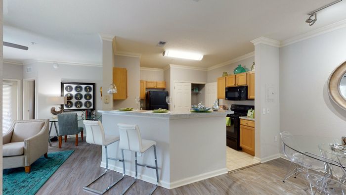 staged model of kitchen and dining room with wood cabinets, granite style counters, and black appliances