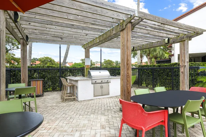 Grilling area with stainless steel grill, tables and chairs, bar top and bar chairs