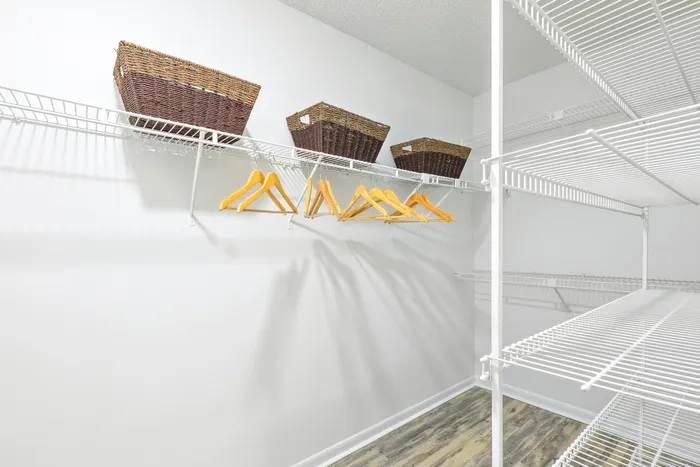 Walk in closet with hardwood style flooring, shelved racks, clothes hangers, and baskets