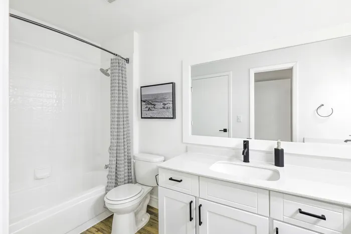 Bathroom, hardwood style flooring, large mirror, curved shower rid, rainfall showerhead