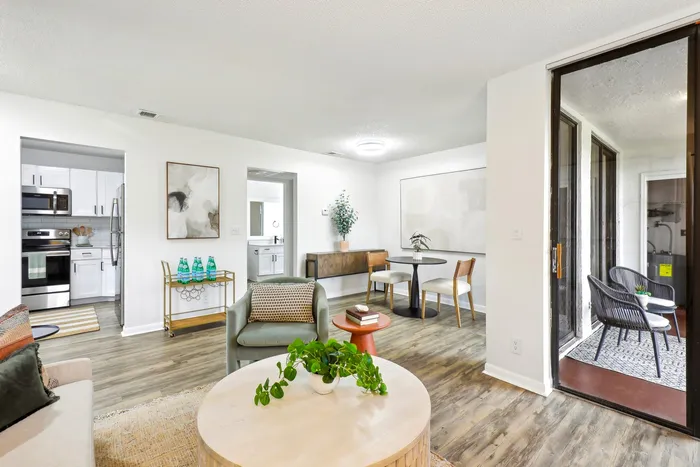 Living room, staged furniture, hardwood flooring, floor to ceiling patio glass door, view of renovated kitchen