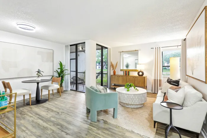 Living room, white couch, circular coffee table, hardwood-style floors, floor to ceiling glass patio doors