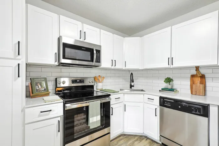 Renovated kitchen with stainless steel oven, microwave, and dishwasher, white quartz counters, white subway tile backsplash