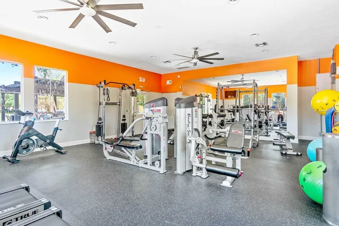 fitness center strength machines, stationary bike, ceiling fans, medicine balls, wall sized mirror