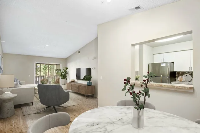 hardwood style flooring, wall opening to view kitchen, stainless steel refrigerator, white cabinetry, living room, white couch, entertainment system, glass patio doors