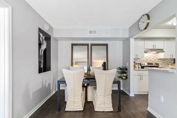 Dining nook, hardwood style flooring, wooded dining table with white chairs, opening to kitchen