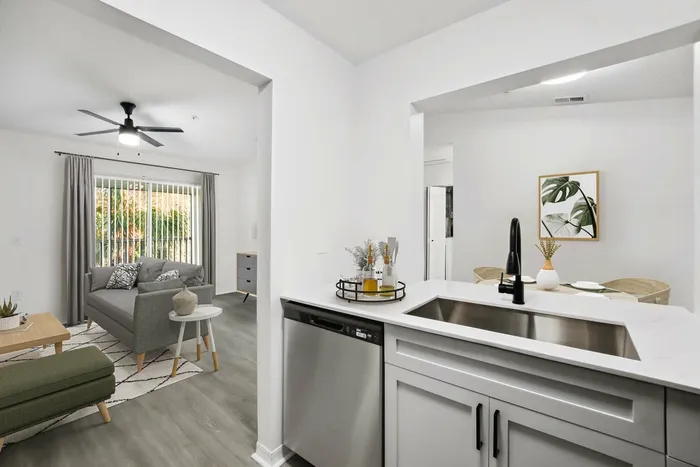 Stainless steel appliances, hardwood style flooring, ceiling fan light fixture, gray couch, glass patio door