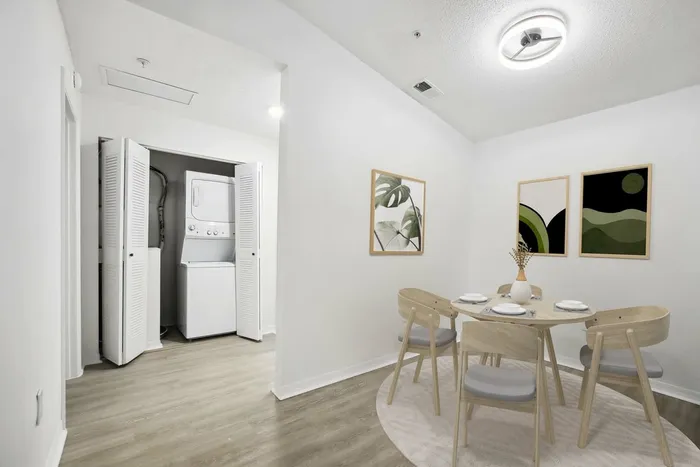 Dining area with wooded table and chairs, laundry area with stacked washer and dryer