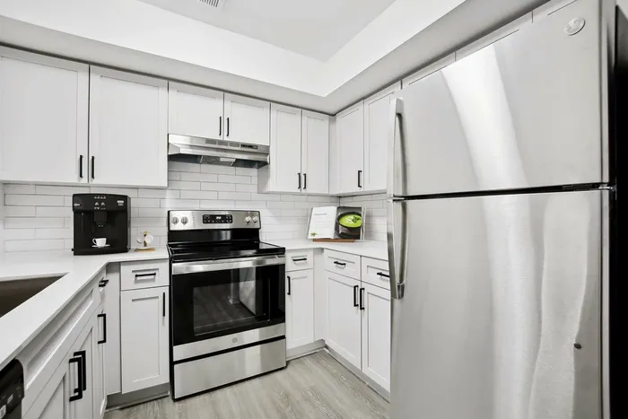 itchen with white quartz counters, stainless steel appliances, white subway tile backsplash, undermount sink with gooseneck faucet, hardwood style flooring
