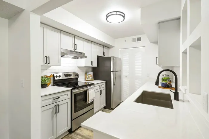 Kitchen, white quartz counters, stainless steel oven and refrigerator, white subway style backsplash, shaker cabinets, hardwood style flooring, undermount sink with gooseneck faucet