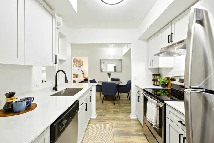 Kitchen, white quartz counters, stainless steel oven and refrigerator, white subway style backsplash, shaker cabinets, round dining table, blue felt chairs