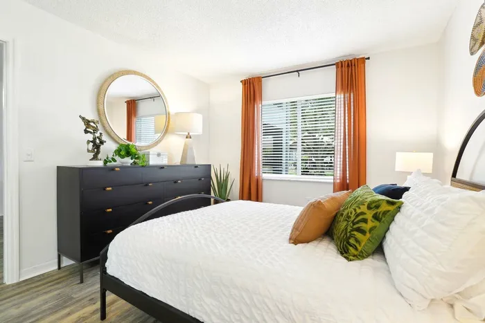 Bedroom, hardwood style flooring, twin bed with black framing, large window, circular wall art, black dresser, circular wall mirror