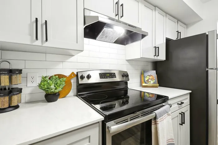 Kitchen, white quartz counters, stainless steel oven and refrigerator, white subway style backsplash, shaker cabinets