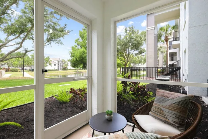 Screened in patio, wooden lounge chair, grass and garden bed, round table