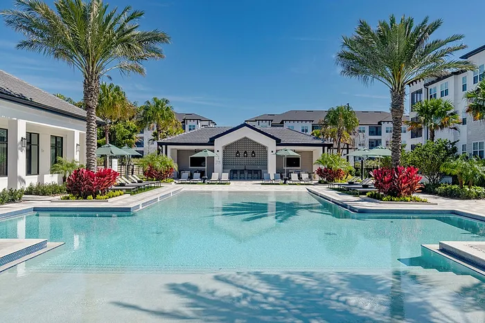 Expansive pool, sundeck, lounge chairs and palm trees