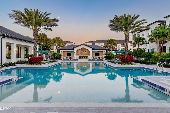 Expansive pool, sundeck, lounge chairs and palm trees