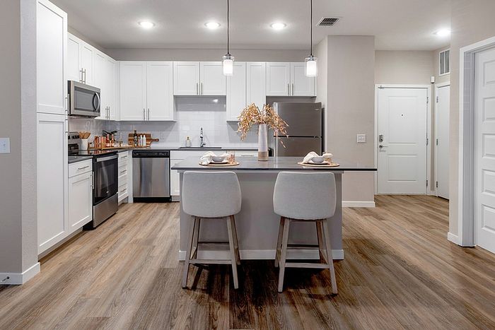 Renovated kitchen with white cabinets and wood style flooring