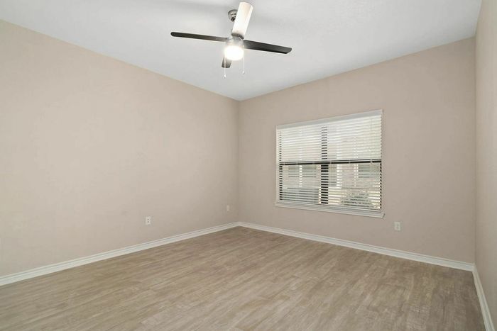 Bright, modern bedroom with elegant wood flooring, fresh paint, and large window offering ample natural light.