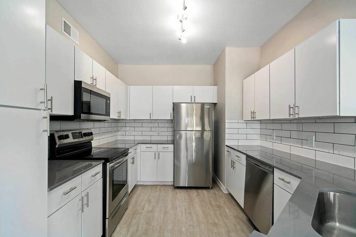 Modern kitchen with sleek white cabinetry, stainless steel appliances, and elegant backsplash tiles.