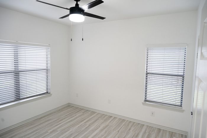Bright, modern bedroom with elegant wood flooring, fresh paint, and large window offering ample natural light.