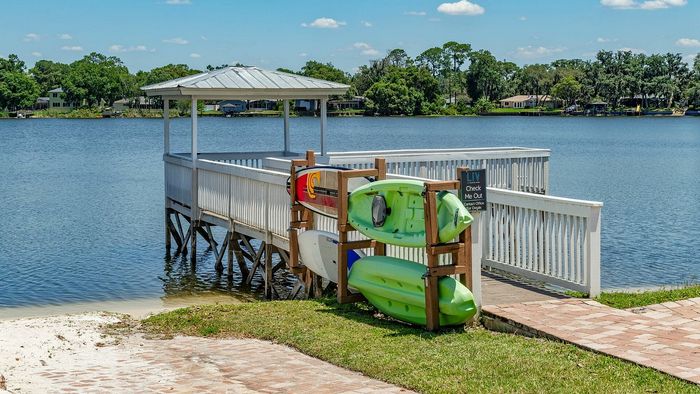 Charming lakeside dock with kayaks and paddleboards under a clear blue sky, perfect for water adventures and relaxation.