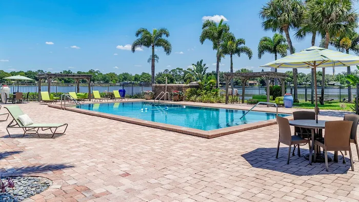 Inviting poolside oasis with elegant lounge chairs and palm trees, perfectly complemented by a serene lake view.
