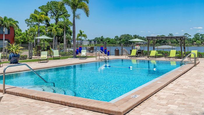 Luxurious outdoor swimming pool surrounded by lush greenery and stylish lounge chairs, offering a serene lakeside view.