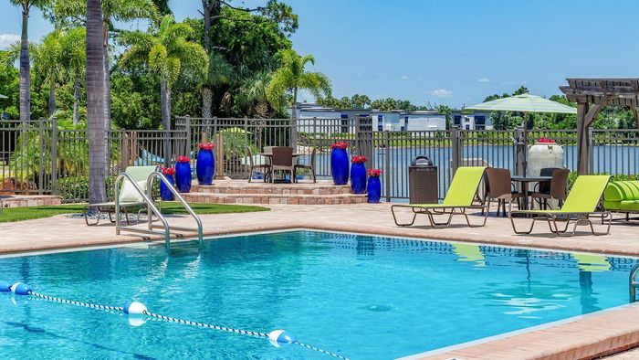 Luxurious outdoor pool area with elegant lounge chairs, vibrant blue planters, and tranquil lakeside views, perfect for relaxation and leisure.
