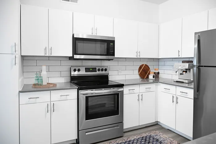 Modern kitchen featuring sleek white cabinets, stainless steel appliances, and elegant countertops, offering a stylish and functional space.