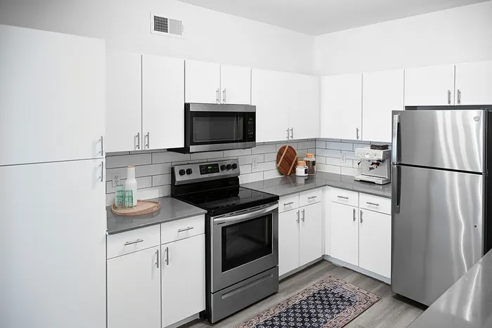 Modern kitchen with sleek stainless steel appliances, elegant white cabinetry, and a stylish backsplash.