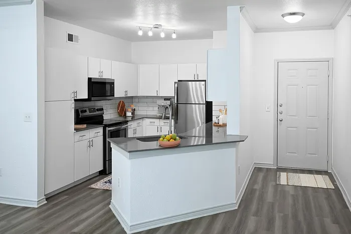 Modern kitchen with sleek stainless steel appliances, stylish white cabinetry, and elegant gray countertops.