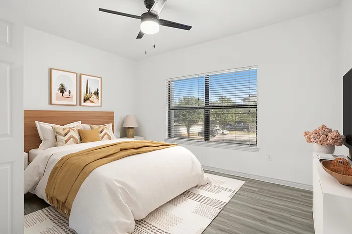 Bright and airy bedroom featuring stylish decor, modern ceiling fan, and a scenic window view.