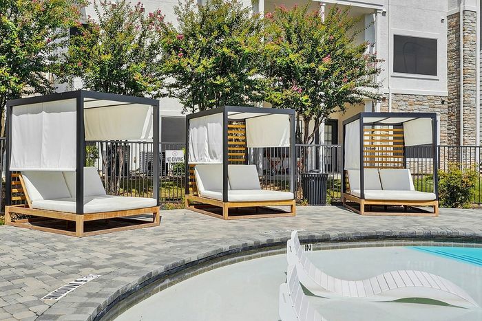 Elegant poolside cabanas with modern wooden frames and plush seating, perfect for relaxing by the sparkling water.