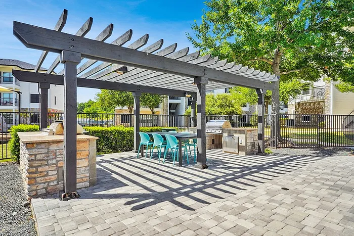 Charming outdoor BBQ area with stylish pergola, modern grill, and vibrant seating, perfect for entertaining in a lush garden setting.