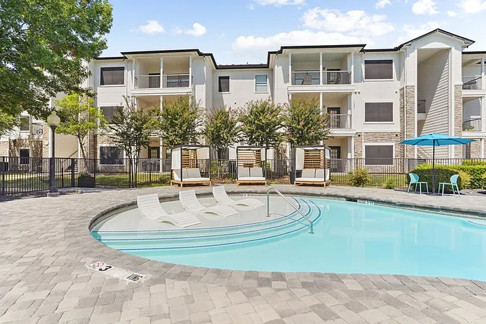 Luxurious community featuring an inviting swimming pool surrounded by stylish lounge chairs and umbrellas, perfect for relaxation and leisure.