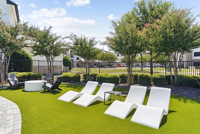 Inviting outdoor leisure area featuring modern white loungers, lush greenery, and elegant landscaping for ultimate relaxation.