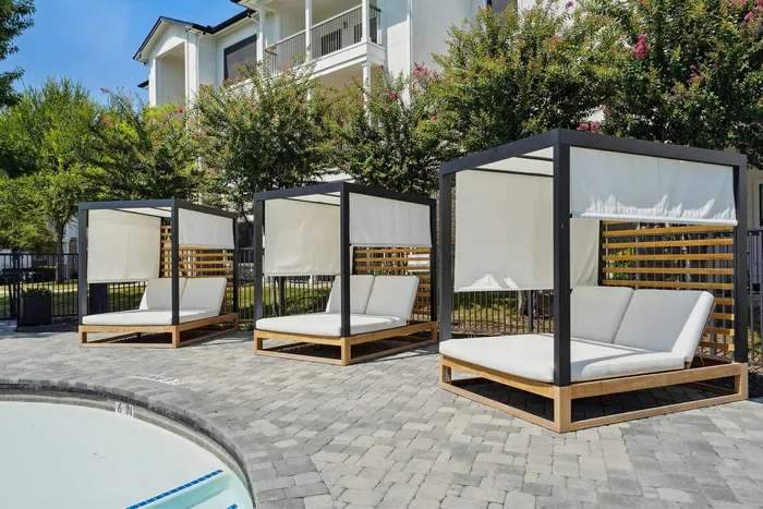 Inviting poolside retreat featuring modern cabanas with plush seating and stylish minimalist design.