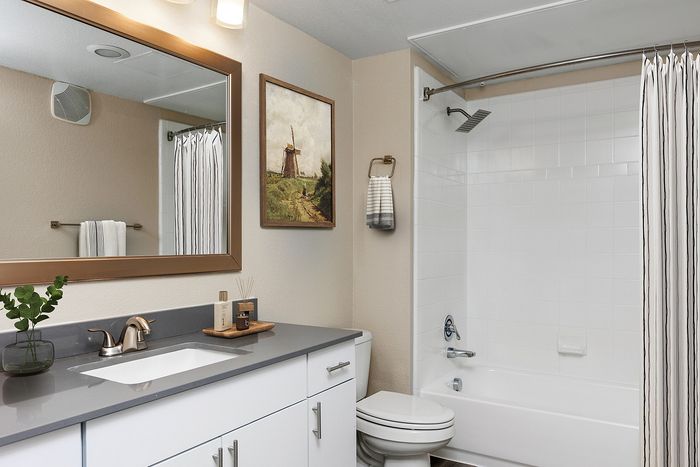 Modern bathroom with sleek gray countertop, stylish fixtures, and decor art piece on the wall.