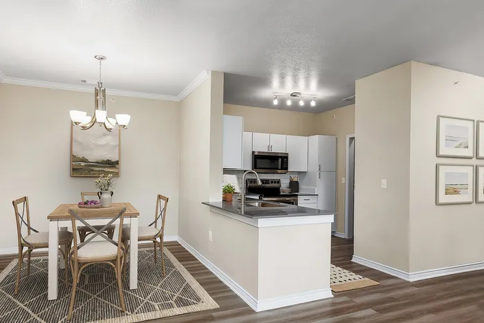 Modern apartment interior featuring a stylish dining area with a wooden table and chic chairs, complemented by a sleek kitchen with contemporary cabinetry and stainless steel appliances.