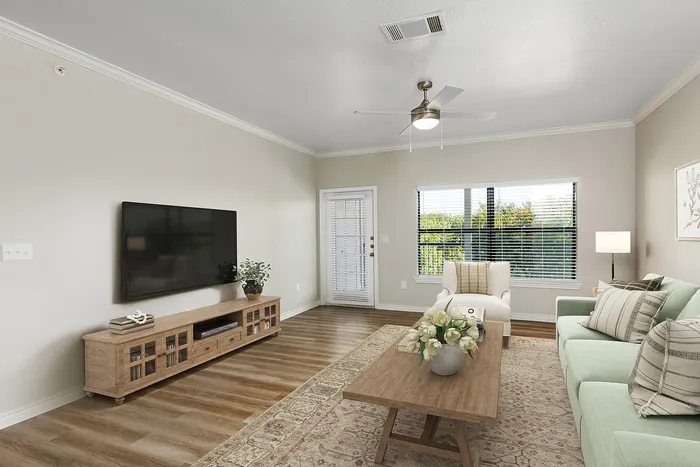 Chic living room with elegant decor, featuring a mint green sofa, stylish wooden furniture, and abundant natural light from large windows.