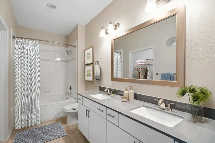 Bathroom with dual sinks, large mirror, and a modern shower area, designed for comfort and style.